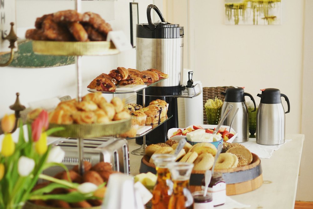A breakfast table laid with pastries, bread, jams and flasks of coffee