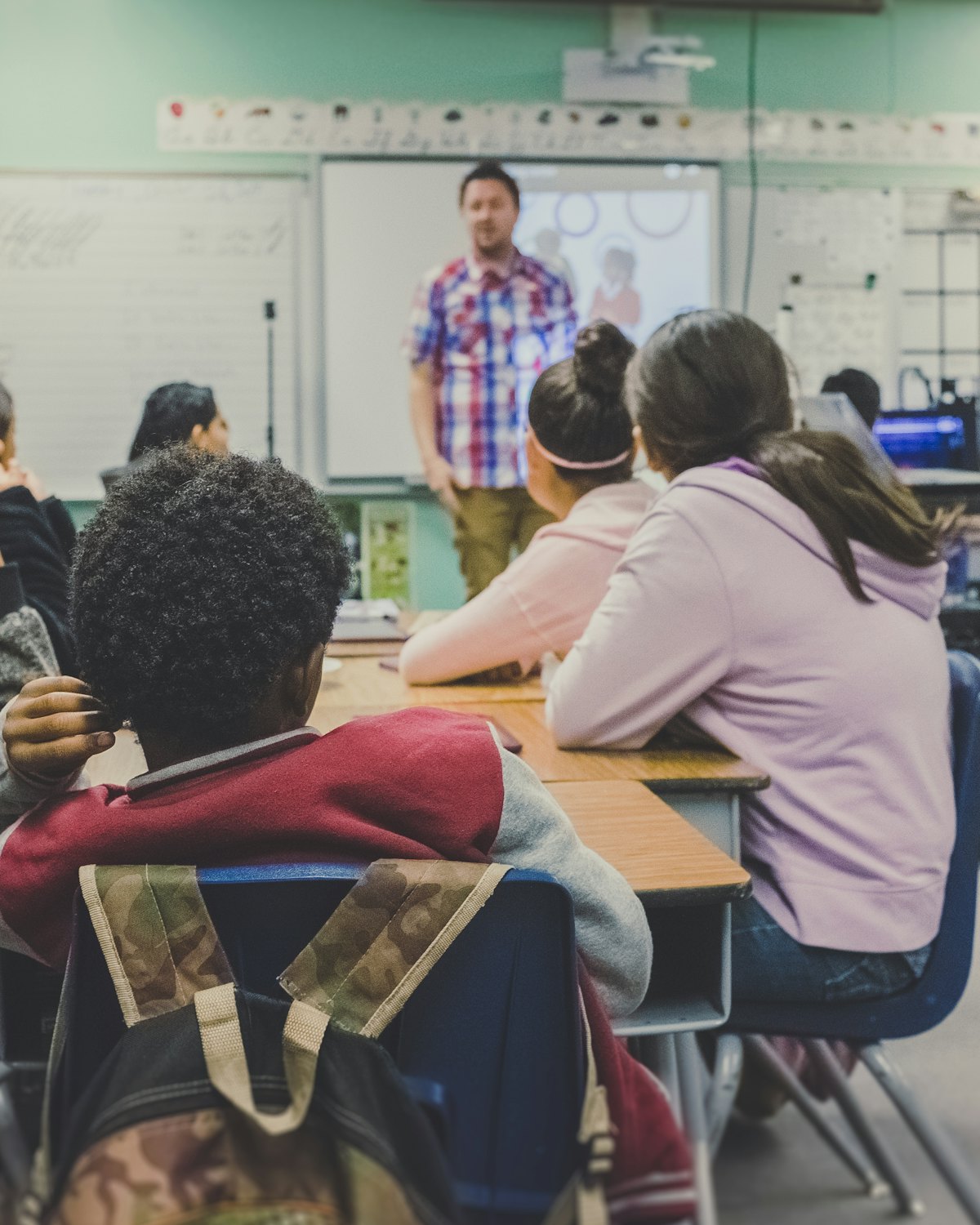 A teacher at the front of a classroom, with pupils listening at their desks