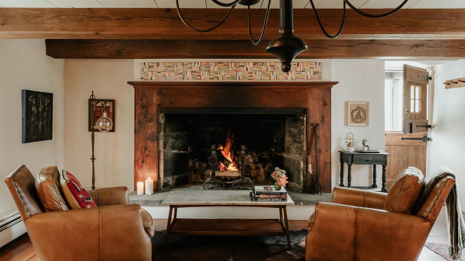 A common room with leather sofas arranged around a lit fireplace