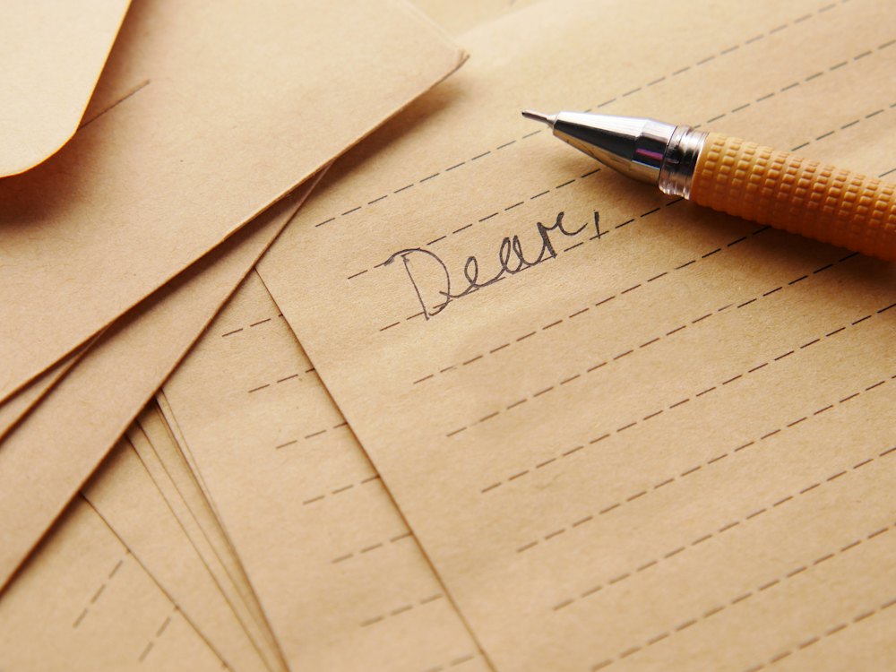 A fountain pen resting on a handwritten letter that begins with the word Dear