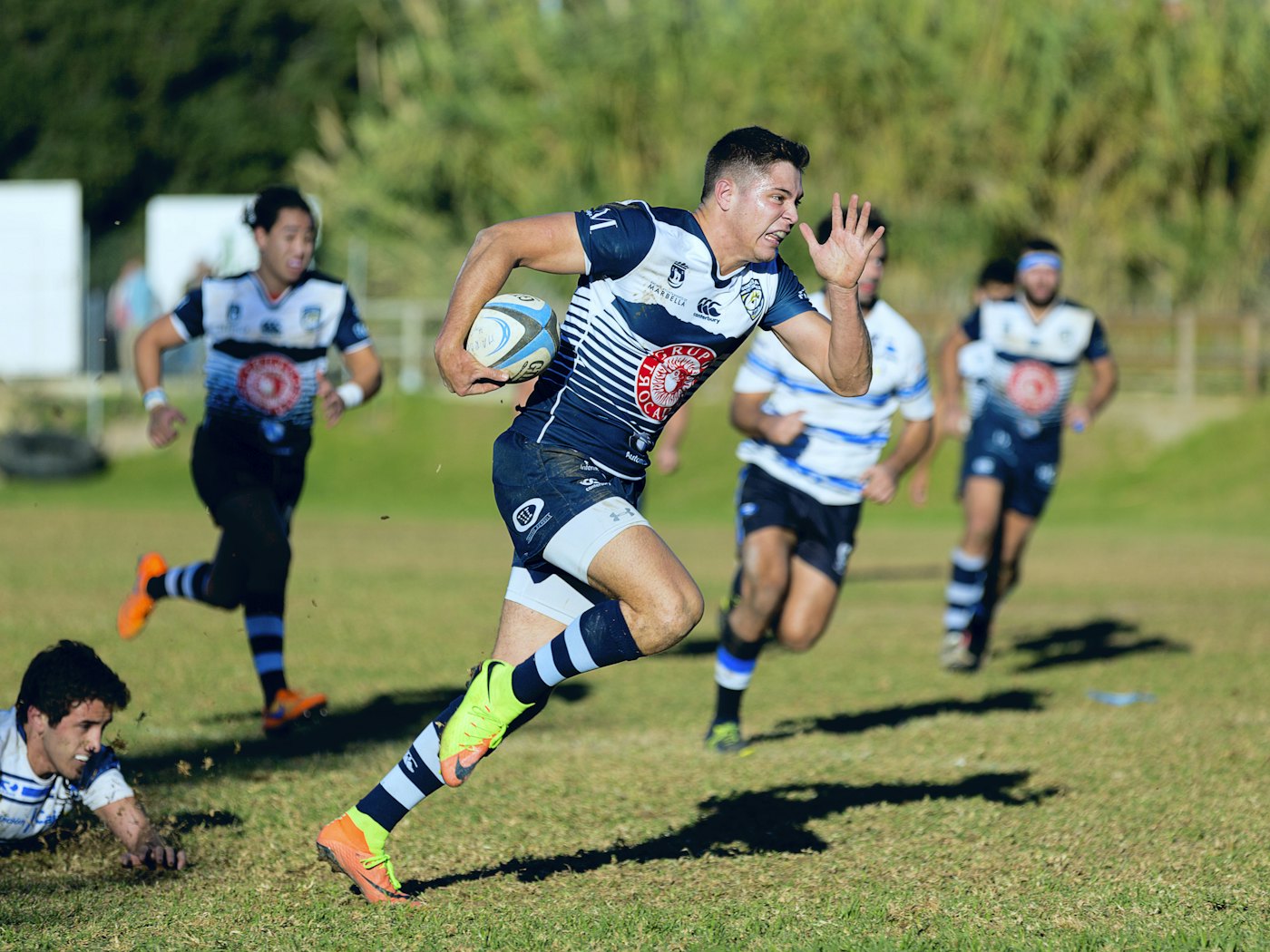 A rugby player sprinting clear with the ball as teammates follow