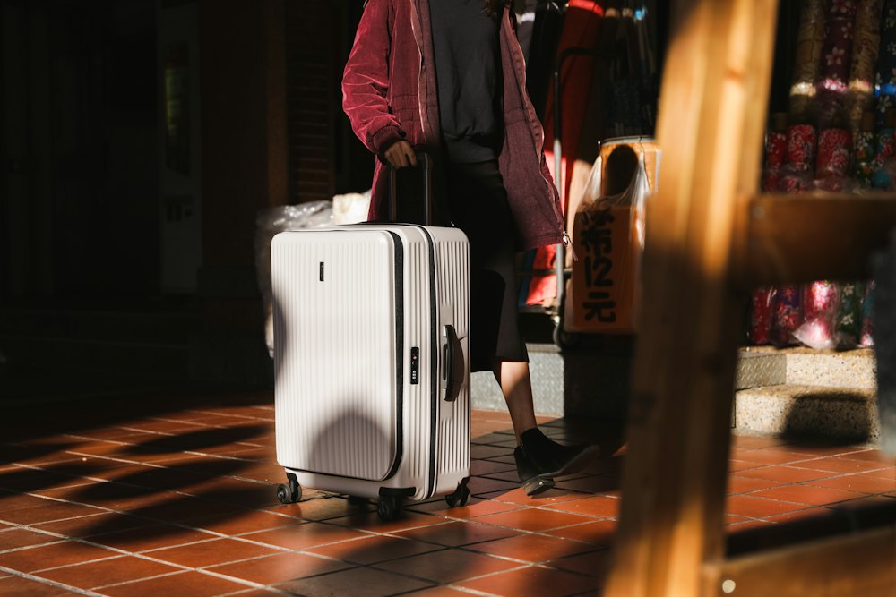 A traveller arriving with a white suitcase in a warmly lit hallway