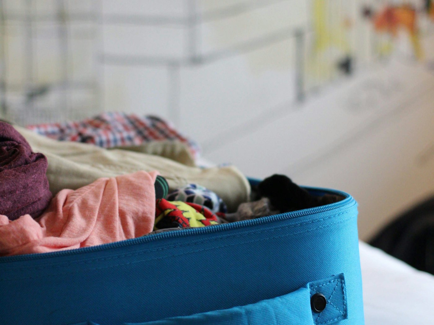 An open blue suitcase full of folded clothes, ready to be unpacked